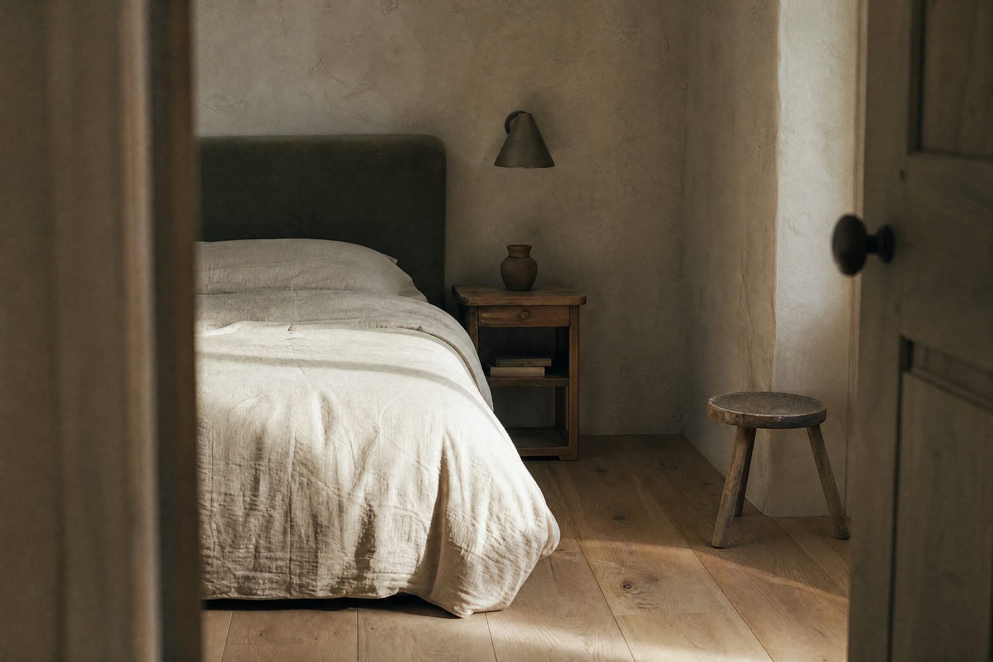 An empty made bed in an empty room, seen from the doorway